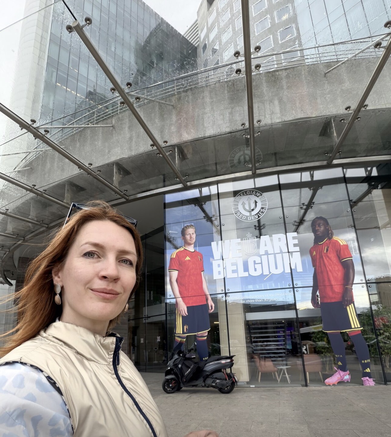 Luba Karpova outside a building fronted by a large Belgian Red Devils campaign display.